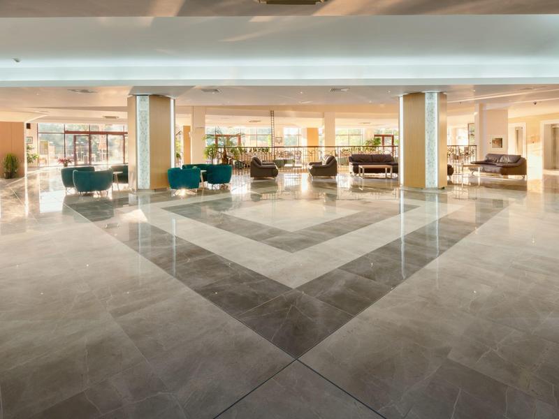 Ruime moderne hotelhal met lichte muren, zithoeken en glanzende vloeren.