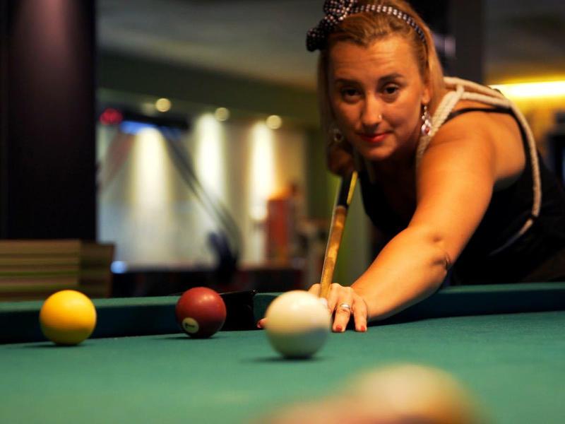 Vrouw leunend over de pooltafel om te schieten.