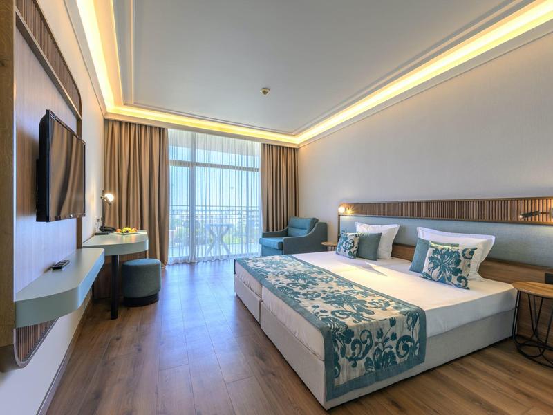 Moderne hotelkamer met tweepersoonsbed, tv en balkon met gordijnen