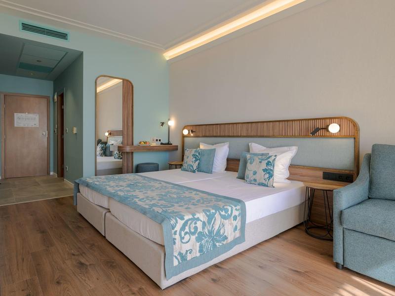 Moderne hotelkamer met tweepersoonsbed, nachtlampen, spiegel en gezellige zithoek.