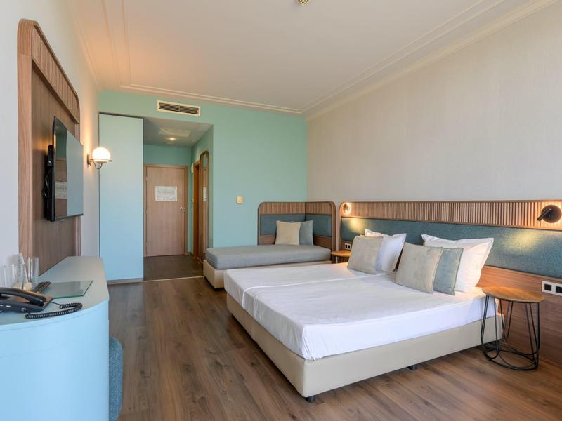 Modern hotelkamer met twee bedden, blauwe muren en houten vloer