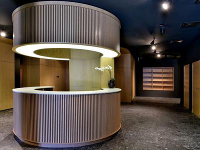 Modern reception area with round desk and warm lighting in a dark setting.