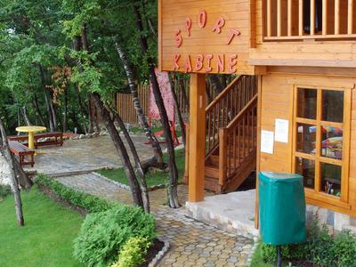 Casa di legno con balcone e sentiero lastricato circondata da prato verde e alberi