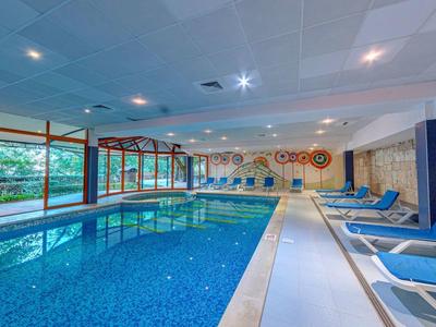 Indoor pool with blue loungers and large windows overlooking greenery.
