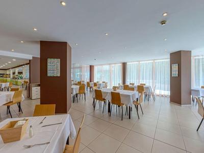 Bright, modern hotel lounge with large windows and white-set tables.