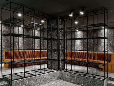 Modern seating area with orange upholstered furniture and black metal grids against gray walls.