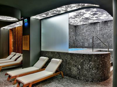 Luxurious spa lounge with marble pool and wooden loungers under soft lighting