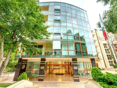 Edificio moderno in vetro con alberi e diverse bandiere all'ingresso