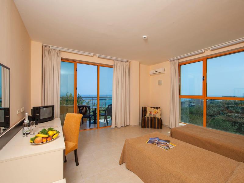 Bright hotel room with two beds and large windows offering a sea view.