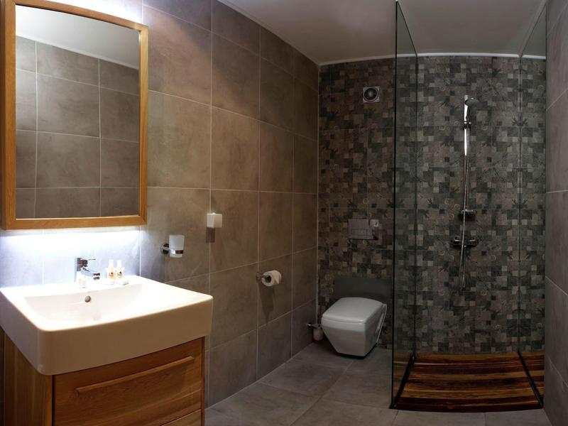 Modern bathroom with shower, sink, toilet, and wooden accents.