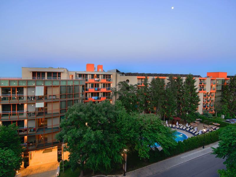 Modern hotel complex surrounded by trees at dusk with clear evening ambiance.