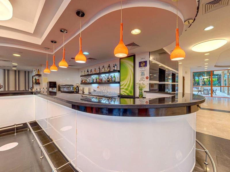 Modern hotel bar area with curved counter and bar stools in a warmly lit space