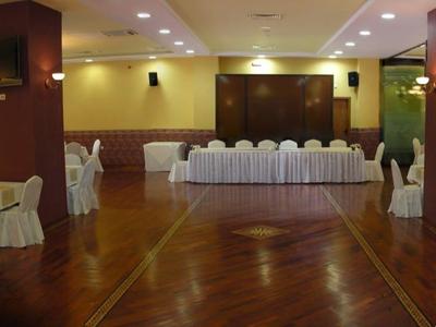 Duża sala bankietowa z okrągłymi nakrytymi stołami i drewnianą podłogą.