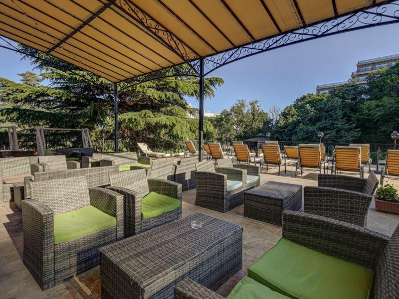 Przytulny salon na świeżym powietrzu z meblami z rattanu i osłoną przeciwsłoneczną w ogrodzie hotelowym.