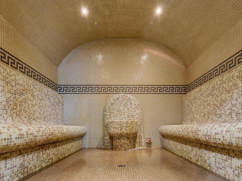 Wnętrze sauny parowej z mozaikowymi płytkami i dwoma długimi ławkami
