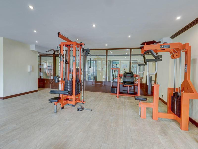 Nowoczesna siłownia z różnymi urządzeniami do ćwiczeń i dużymi przeszklonymi oknami.