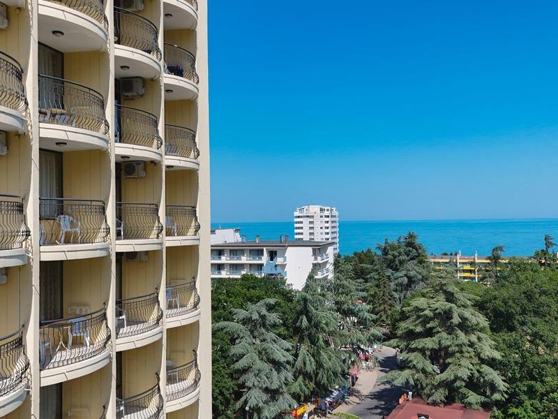 Hotel z balkonami z widokiem na zielone drzewa i niebieskie morze pod czystym niebem.