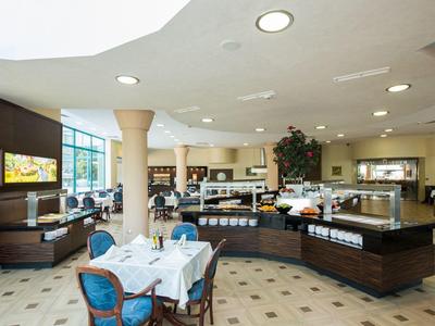 Jasna, nowoczesna restauracja z dużymi oknami i elegancko nakrytymi stołami.