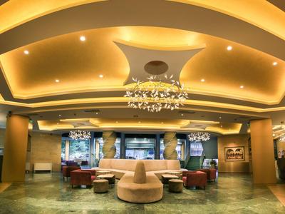 Elegancki hol hotelowy z ciepłym oświetleniem, okrągłymi miejscami do siedzenia i nowoczesnymi żyrandolami.