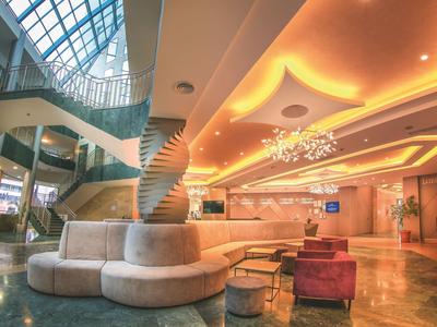 Moderne hotel lobby met ronde zitbank, spiraalvormige zuil en grote ramen.