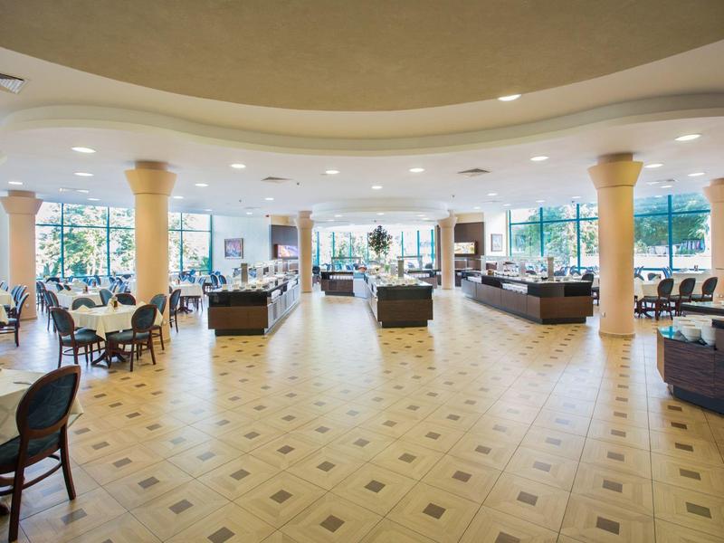 Przestronny, jasno oświetlony hol hotelowy z kolumnami i miejscami do siedzenia.