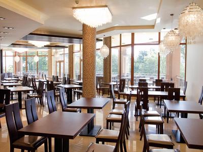 Jasna, nowoczesna jadalnia z drewnianymi krzesłami i dużymi oknami wpuszczającymi światło dzienne.