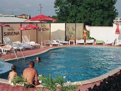 Piscina rotonda con diverse persone e sdraio in un ambiente alberghiero.