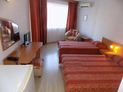 Camera d'albergo con due letti singoli, finestra, scrivania, TV e poltrona.