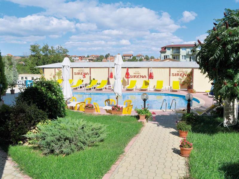 Piscina esterna riscaldata con lettini e ombrelloni in giardino di un hotel.
