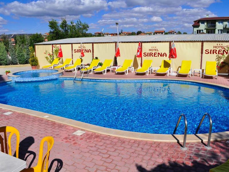 Una piscina all'aperto con lettini gialli e muri pubblicitari sotto un cielo azzurro.