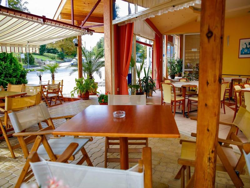 Accogliente area esterna coperta di un ristorante con sedie e tavoli in legno.