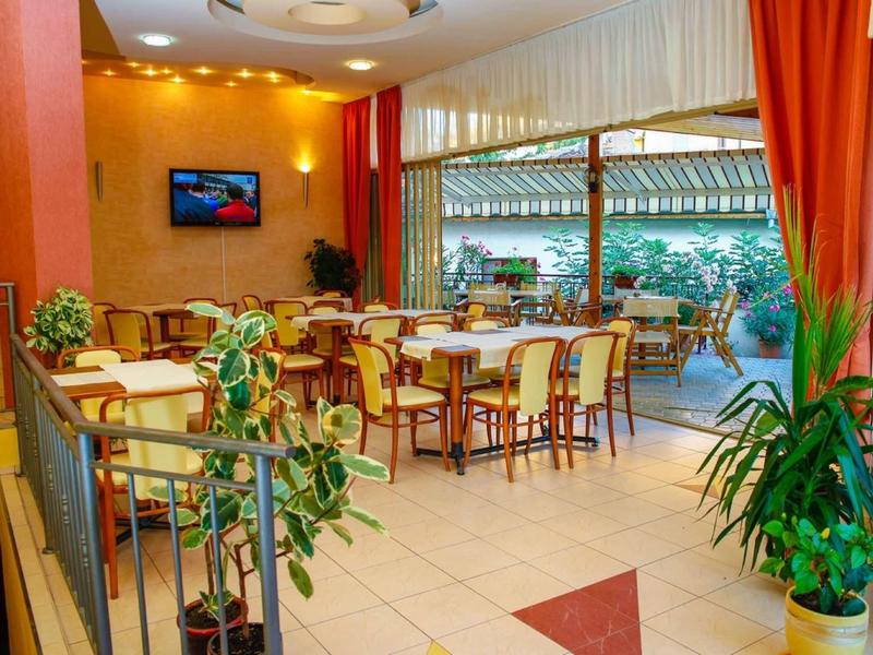 Ristorante luminoso con tavoli e sedie, piante e un'area aperta che si affaccia sulla terrazza.