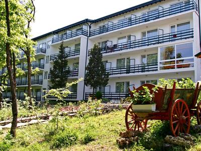 Nowoczesny budynek hotelu z balkonami i ogrodem z starym drewnianym wozem na pierwszym planie