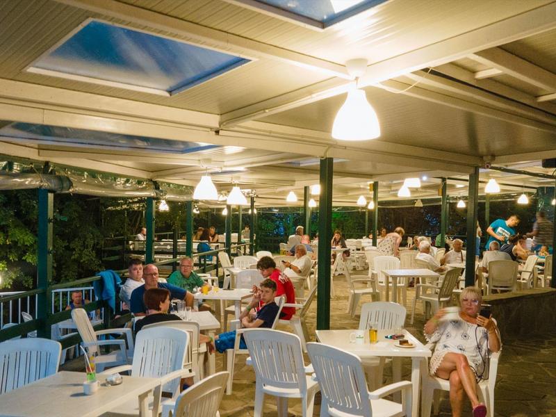 Pohodlná terasa s židlemi a stoly, hosté sedí a relaxují večer.