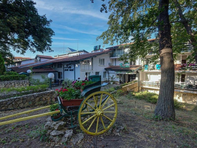 Tradiční kočár tažený koňmi před venkovskou hospodou pod stromy za jasného dne.