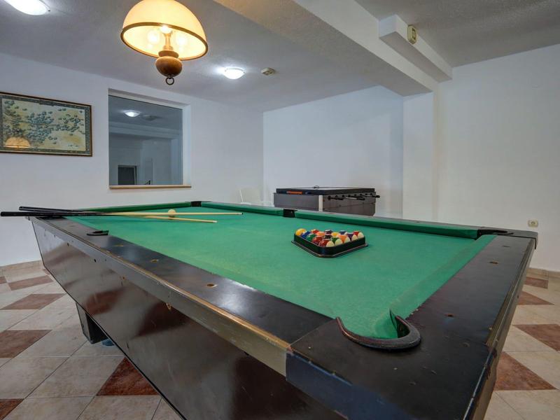 Stůl na kulečník s rámovaným obrazem a stolní fotbal v světlé herně.