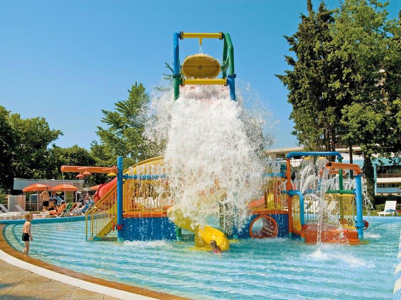 Vodní bazén se skluzavkou a velkým kýblem vody v hotelovém vodním parku.