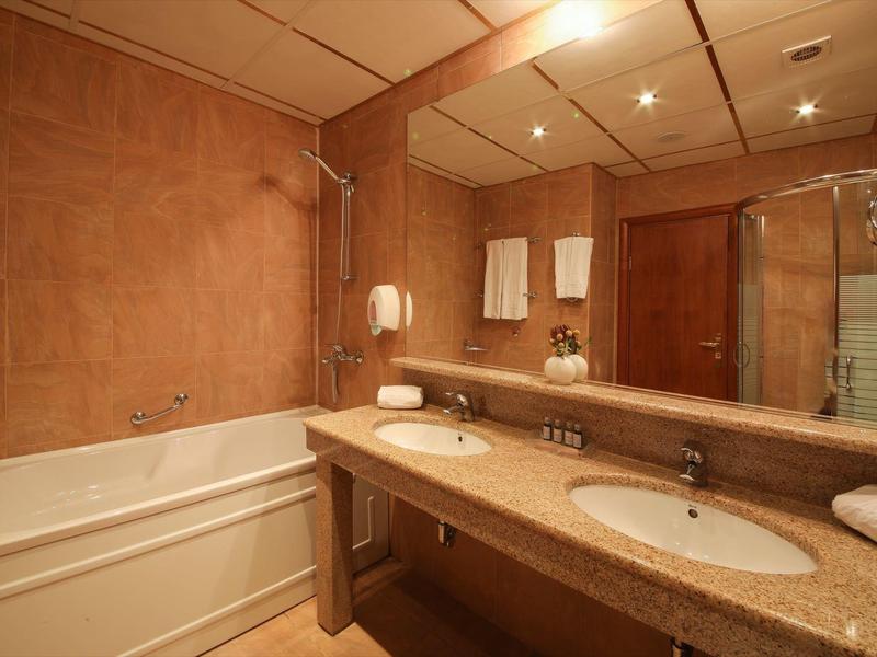 Moderní koupelna s vanou, dvojnásobným umyvadlem a velkým zrcadlem.