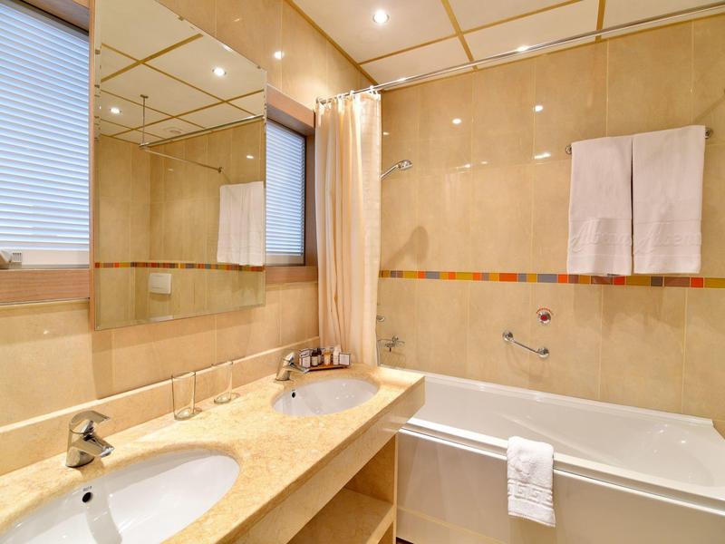 Moderní koupelna s dvojitým umyvadlem, velkým zrcadlem a vanou s koupací závěsem.