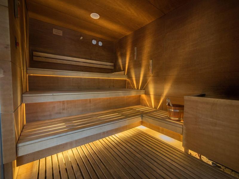 Moderní sauna s dřevěnými lavicemi a teplým nepřímým osvětlením