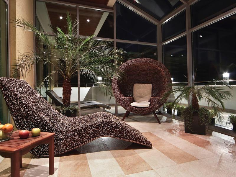 Moderní zimní zahrada se dvěma pohodlnými křesly a květinami v květináčích v noci.