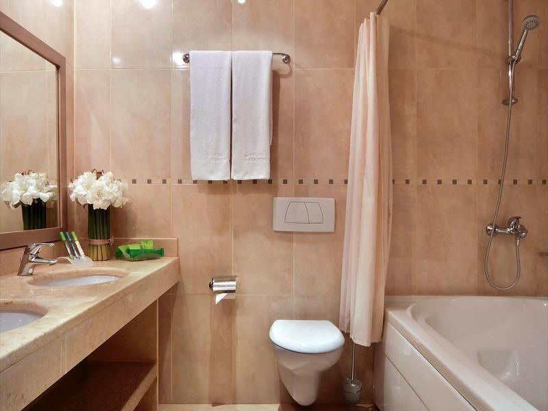 Moderní koupelna se dřezem, toaletou, vanou a ručníky zavěšenými na zdi.