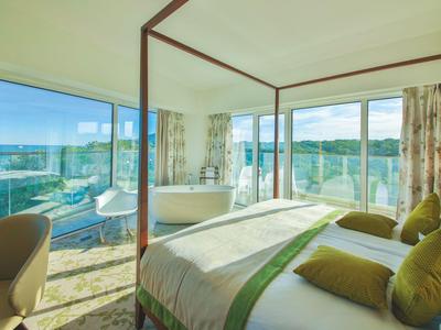 Nowoczesny pokój hotelowy z łóżkiem z baldachimem i dużymi oknami z widokiem na miasto.