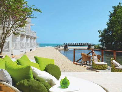 Wygodne leżaki z zielonymi poduszkami na słonecznej plaży z widokiem na morze.