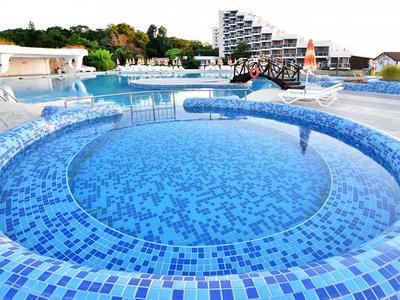 Runder blauer Mosaik-Pool mit umliegendem Hotelgebäude im Hintergrund.
