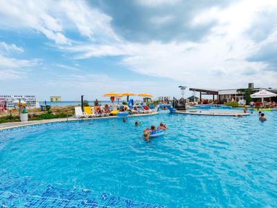 Grande piscine extérieure avec des personnes et des parasols par une journée nuageuse.