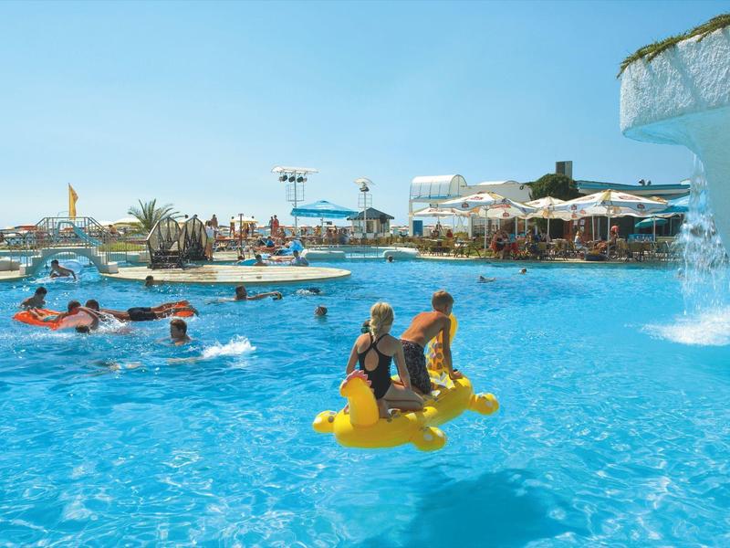 Ludzie odpoczywają i bawią się w dużym basenie pod czystym niebem z atrakcjami wodnymi.