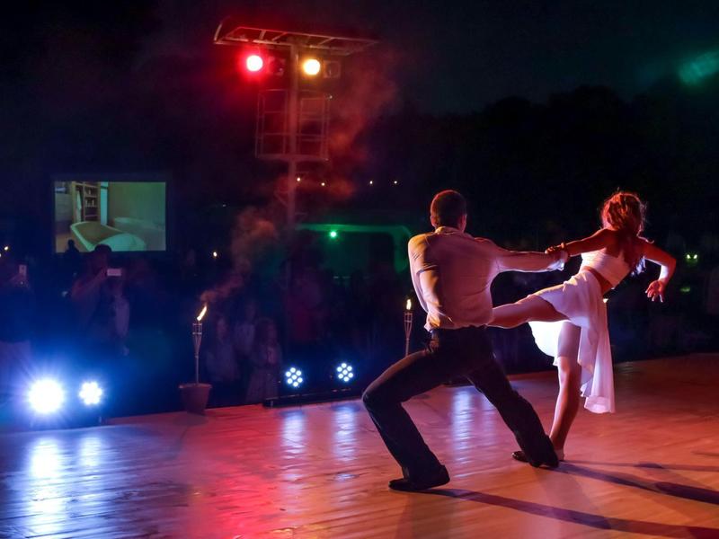 Para tancerzy wykonuje elegancki ruch na oświetlonym parkiecie na nocnym wydarzeniu.