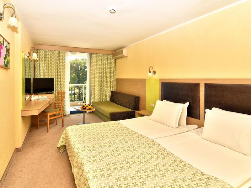 Jasny pokój hotelowy z dwoma pojedynczymi łóżkami, miejscem do siedzenia i widokiem na balkon