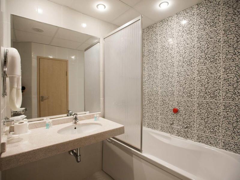 Salle de bain moderne avec lavabo blanc et baignoire avec mur à motifs